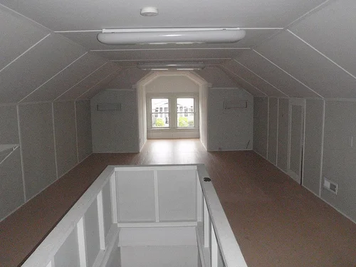 A well-lit attic with wooden beams and flooring