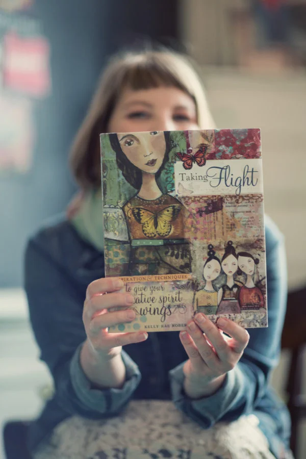 Kelly Rae Roberts holding her book 'Taking Flight'