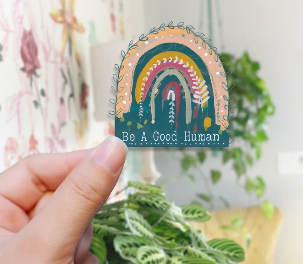 Hand holding sticker with text 'Be a Good 3'